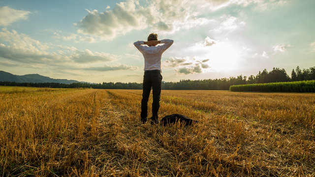 Businessman standing relaxed in harvested field