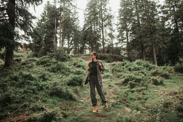 Naklejka premium Splendid nature. Full length portrait of young woman enjoying hike in coniferous wood. She is looking away and smiling