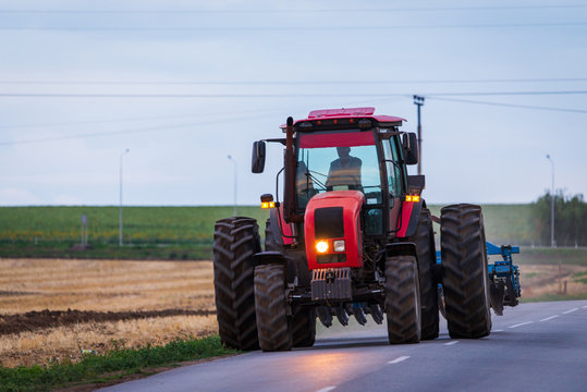 Fototapeta Agricultural tractor moving on the asphalt road after working in field