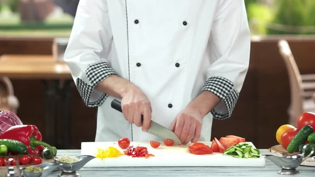 Chef cutting cherry tomato. Food preparation, fresh vegetables.