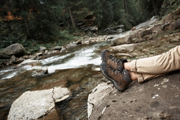 Comfortable footwear. Man in comfortable footwear relaxing in the forest with a mountain river on the background