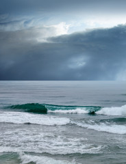 landscape image of beach and waves over stormy sky