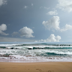 landscape image of sandy beach and waves over stormy sky