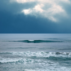 Fototapeta na wymiar Seascape and waves over stormy sky