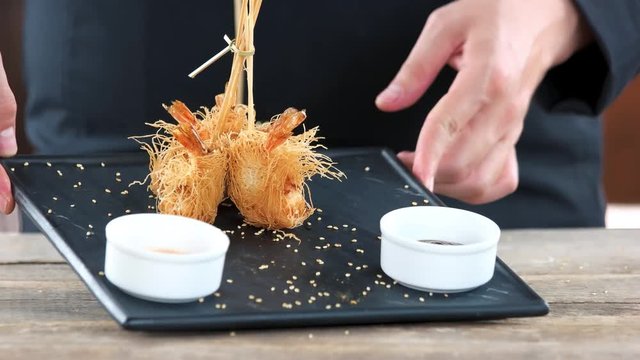 Hands of chef, seafood appetizer. Shrimp tempura, kataifi dough.