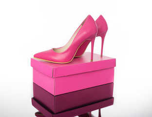 Double pink pointed high heels women's shoe and box on reflective floor