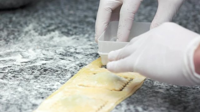 Hands making ravioli. Raw pastry close up.