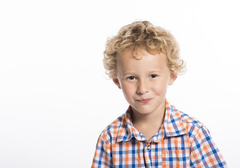 Adorable, curly haired little boy trying not to laugh, isolated on white background
