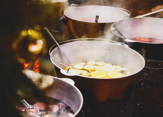 Mulled wine with oranges in large vats on Christmas market. New year and Christmas celebration concept, traditional drink for winter
