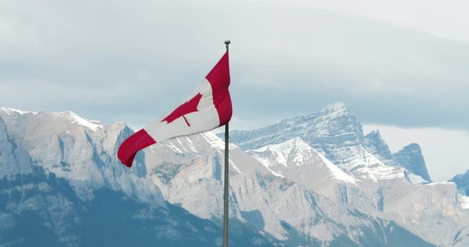 Canadian Flag Blowing in the Wind with Rocky Mountains in the Background, Banff