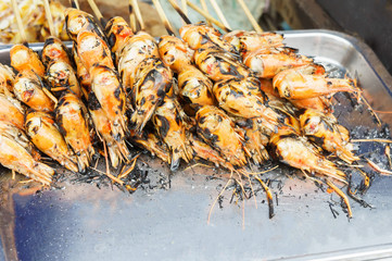 Stack of many grilled shrimp skewer on steel tray in the market. For seafood, food, kitchen, texture and background.