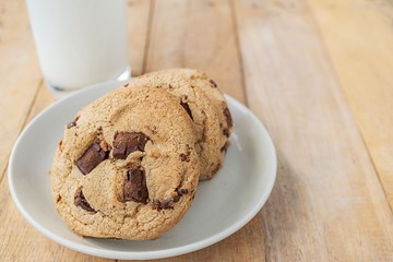 Chocolate cookies and cup of milk on wood table