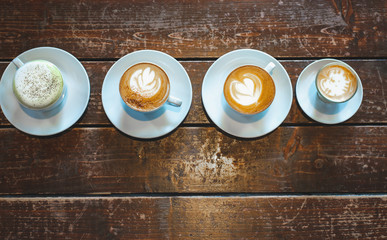 Different cups of coffee and tea cup on wooden table, top view,copy space.