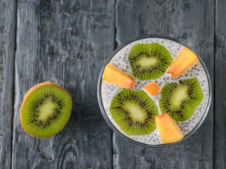 Half kiwi and pudding of Chia seeds, kiwi and peach on the village table.