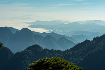 view of the far away mountain range covered in thick white cloud under hush sun light in the hazy morning
