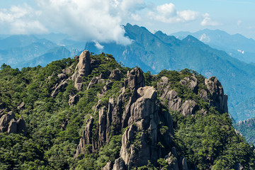 peaks covered with green with unique formation under blue cloudy sky