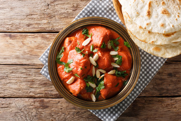 Butter Chicken Murgh Makhani, cooked in a spicy tomato sauce with almonds close-up served with flat bread naan. horizontal top view
