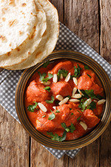 Butter Chicken Murgh Makhani cooked in a spiced tomato gravy close-up in a plate with roti. Vertical top view