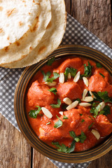 Traditional recipe for butter chicken Murgh Makhani in spicy sauce with almonds and cilantro close-up with roti. Vertical top view