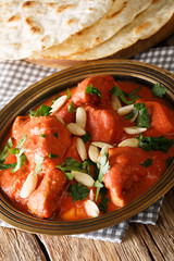 Butter Chicken Murgh Makhani cooked in a spiced tomato gravy close-up in a plate with roti. vertical