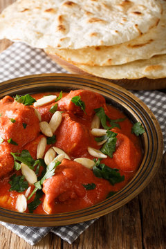 Butter Chicken Murgh Makhani, cooked in a spicy tomato sauce with almonds close-up served with flat bread naan. vertical
