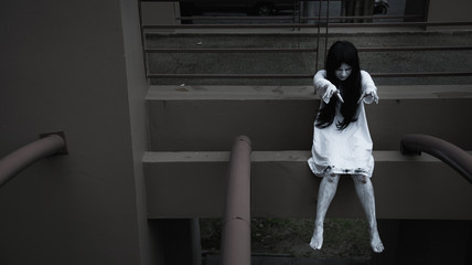 Horror woman ghost creepy sitting hanging legs on building,