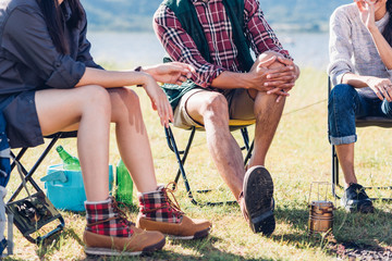 Young couple and friend sitting on chair discuss together on camping tent