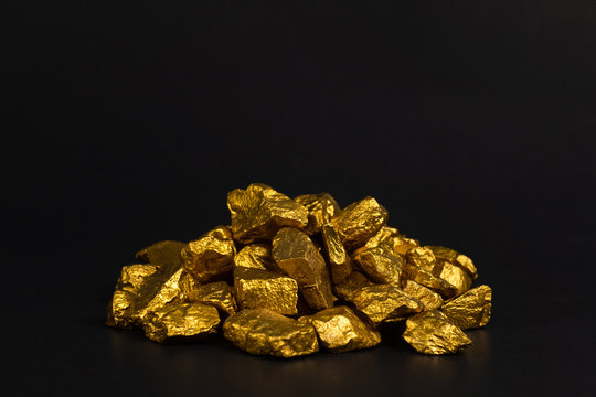 A pile of gold nuggets or gold ore on black background, precious stone or lump of golden stone, financial and business concept.