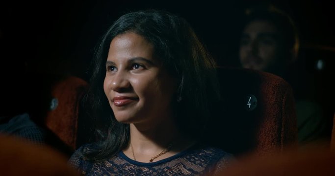 Shocked reaction from woman watching a movie at the movie theatre.