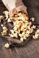 Homemade Kettle Corn Popcorn in a paper bag. Salt popcorn on wooden table. Film concept. Fast food. Top view. Copy space