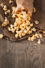 Fototapeta na wymiar Homemade Kettle Corn Popcorn in a paper bag. Salt popcorn on wooden table. Film concept. Fast food. Top view. Copy space
