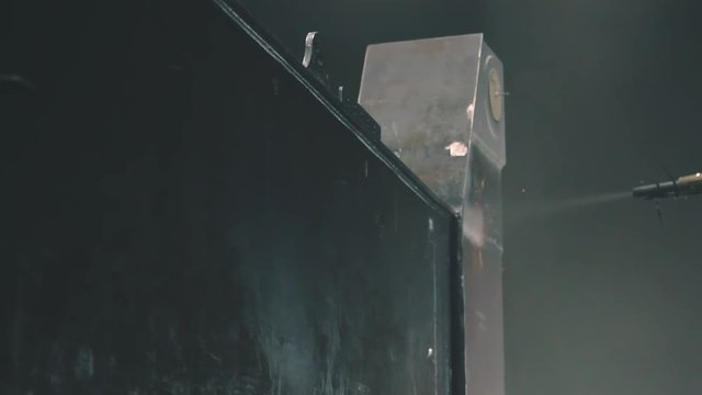 Man cleans metal surface by sandblaster gun in a metal construction factory. Shotblaster in a process