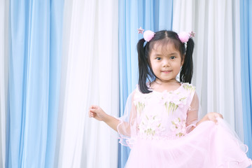 Asian child cute or kid girl smile on wedding ceremony for bridesmaid and princess or fairy on love and wear pink dress on white and blue fabric or cloth scene and background on party stage with space