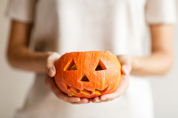 Holidays, halloween, decoration and people concept - close up of woman with pumpkins at home