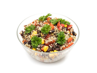 Glass bowl with quinoa salad with red pepper, corn, tomato and black beans, topped with parsley and isolated on white background