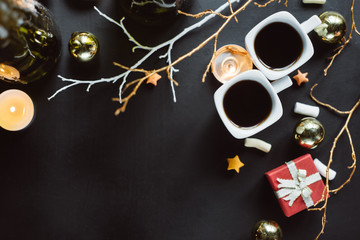 Winter composition. Two cups of coffee, branches, candles and Christmas toys on a dark background. Flat lay