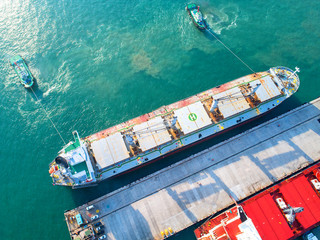 gerneral bulk cargo ship on departure sailing from the seaport terminal, assist by tug boat pulling...
