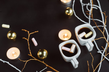 Fototapeta na wymiar Christmas composition. Two cups of coffee with marshmallows, branches, candles and Christmas toys on a dark background. 