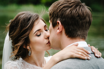 Fototapeta premium Portrait of young wedding couple kissing at nature. Newlyweds.