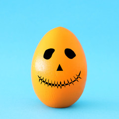 minimal and funny Halloween holiday concept. Orange egg with scary cute face.