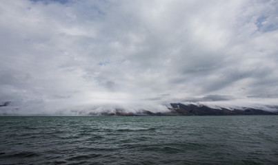 Dramatic view of lake with cloudy mauntains