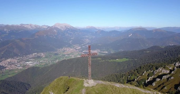 4K Drone aerial view to the Seriana valley and Orobie Alps in a clear and blue day. The cross at the top of the mountain. Landscape from Pizzo Formico Mountain, Bergamo, Italy