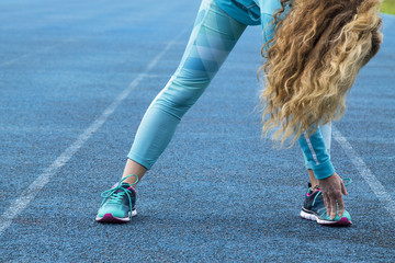 woman doing sport exercises on blue althletic trail