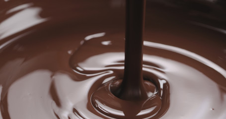 closeup pouring melted dark chocolate from spoon