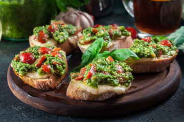 Bruschetta with fresh pesto, mozzarella and cherry tomatoes on cutting board