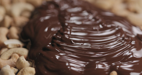 closeup covering roasted cashew with melted dark chocolate
