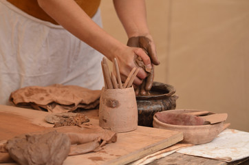 Hand of medieval craftsman female potter preparing clay - moistens and kneads the clay before work