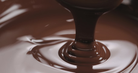 closeup pouring melted dark chocolate from spoon
