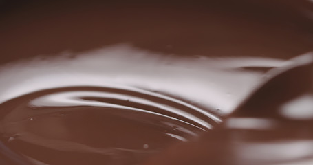 closeup stirring melted dark chocolate with spoon