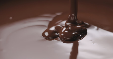closeup pouring melted dark chocolate from spoon